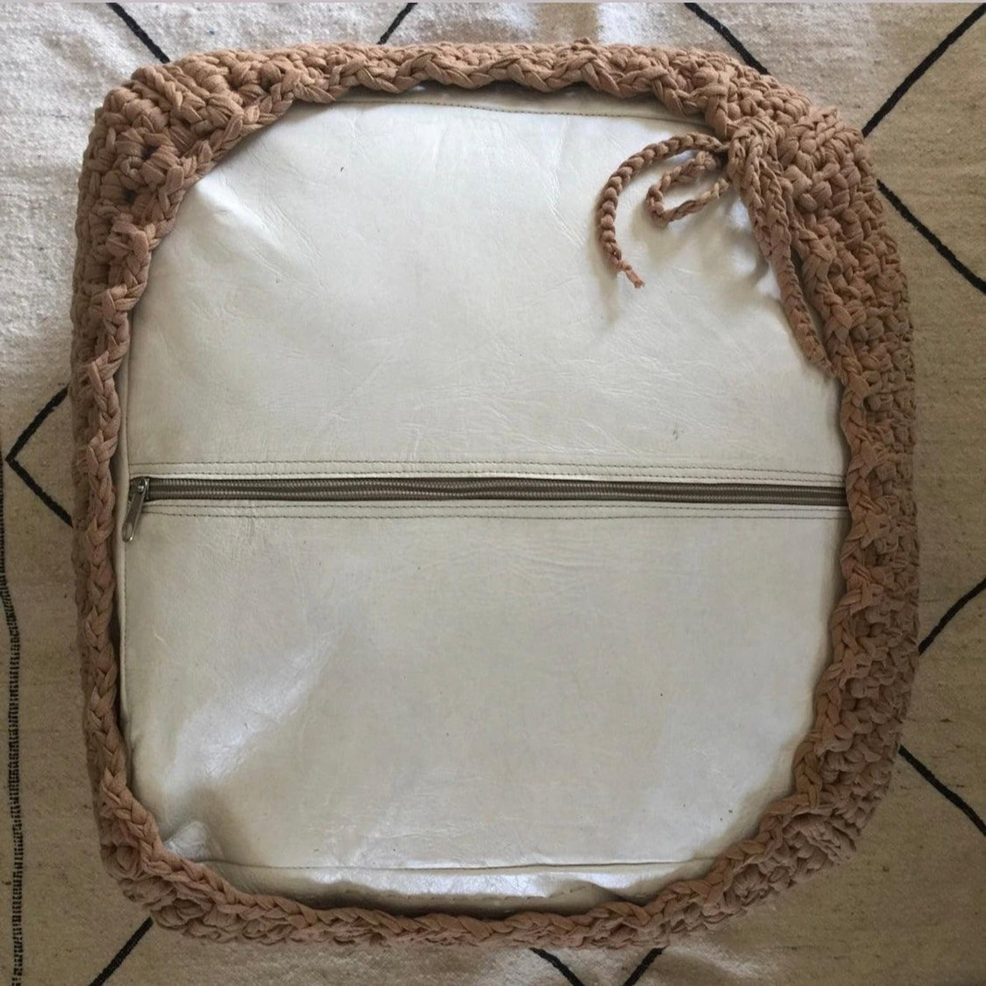 Bottom of a white square ottoman showing how the crochet cover works