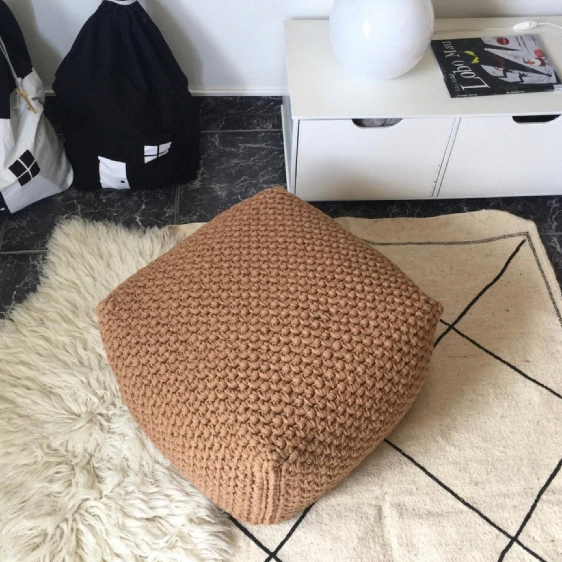Square ottoman cover in camel shade placed on a textured rug
